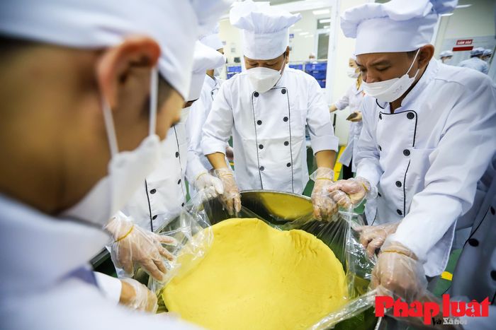 Những người nghệ nhân sẽ bao một lớp giấy chống dính xung quanh thành trong của khuôn rồi lần lượt đặt từng lớp bánh, nhân vào và dàn thật đều sao cho nhân nằm vừa khít trong vỏ bánh. Một chiếc bánh sẽ bao gồm 12 lớp nhân và vỏ.